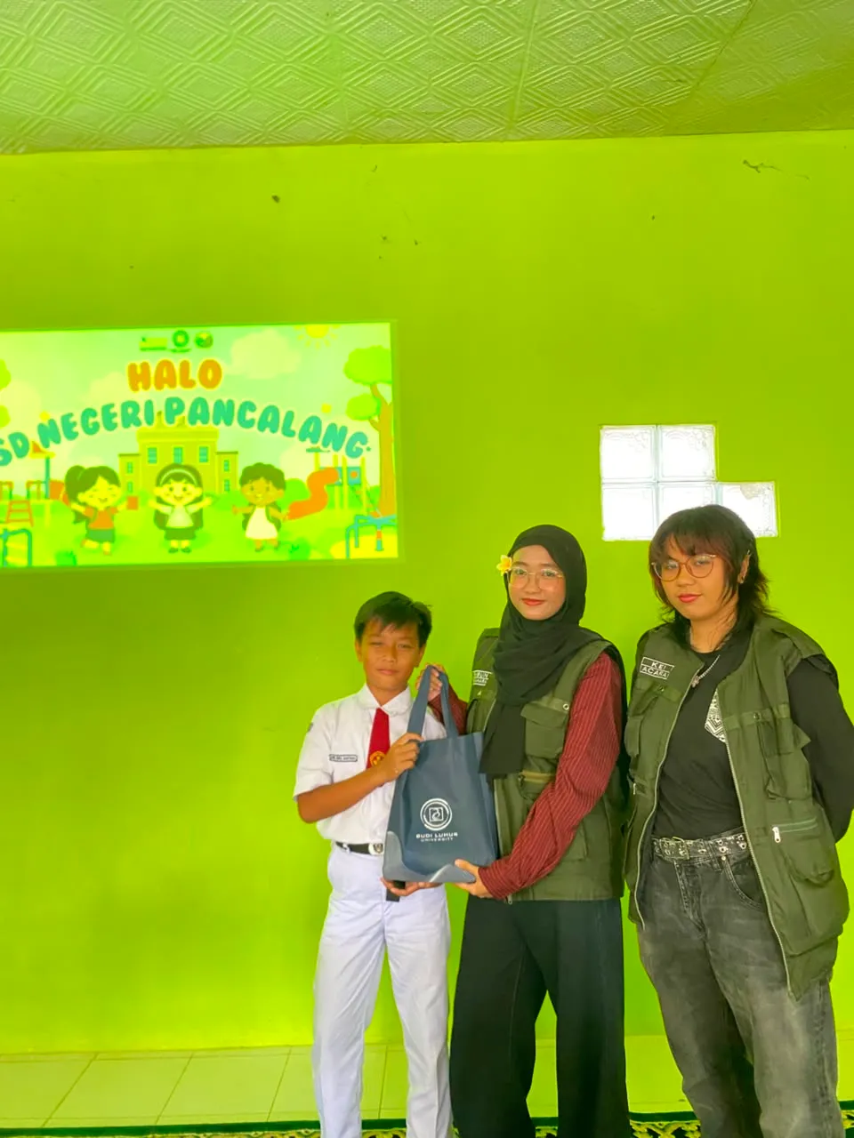 Peserta didik berfoto bersama dua mahasiswa KKN T3 setelah menerima goodie bag.