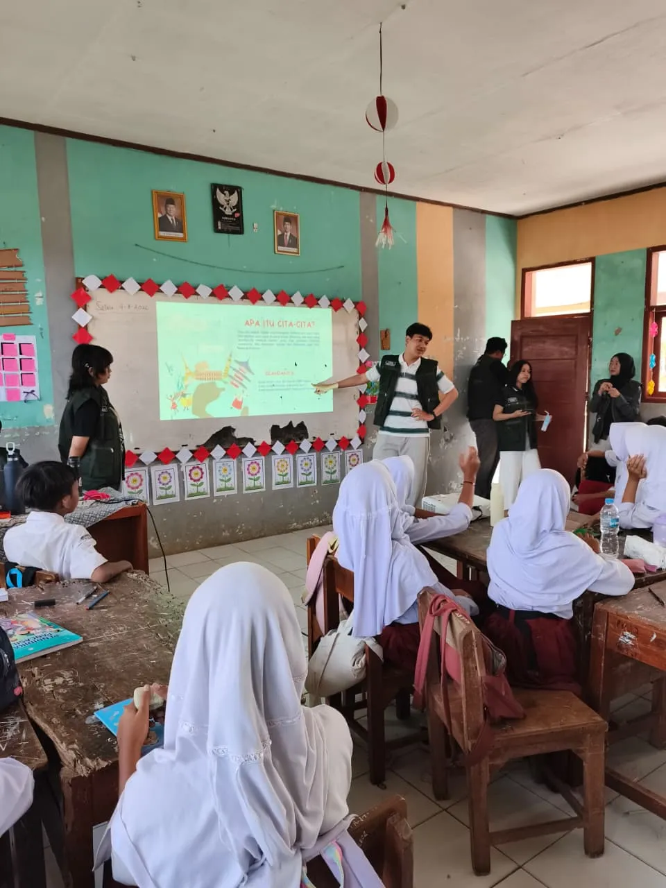 Anggota Tim KKN T3 menunjuk materi presentasi di depan siswa kelas VI SD Negeri Pancalang.