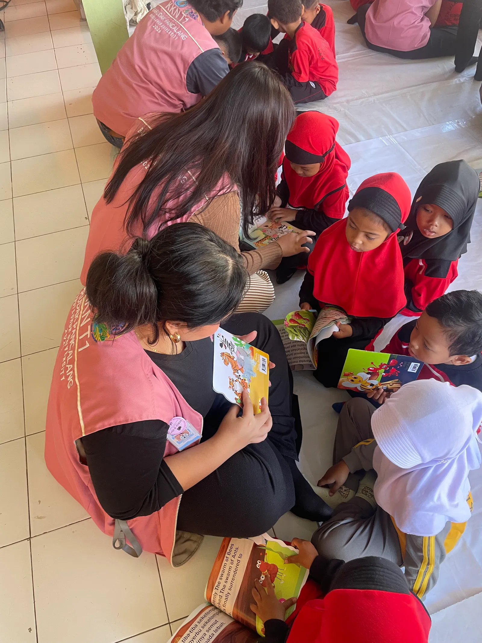 Mahasiswa KKN T1 mendampingi peserta didik membaca buku bergambar dalam kelompok kecil.